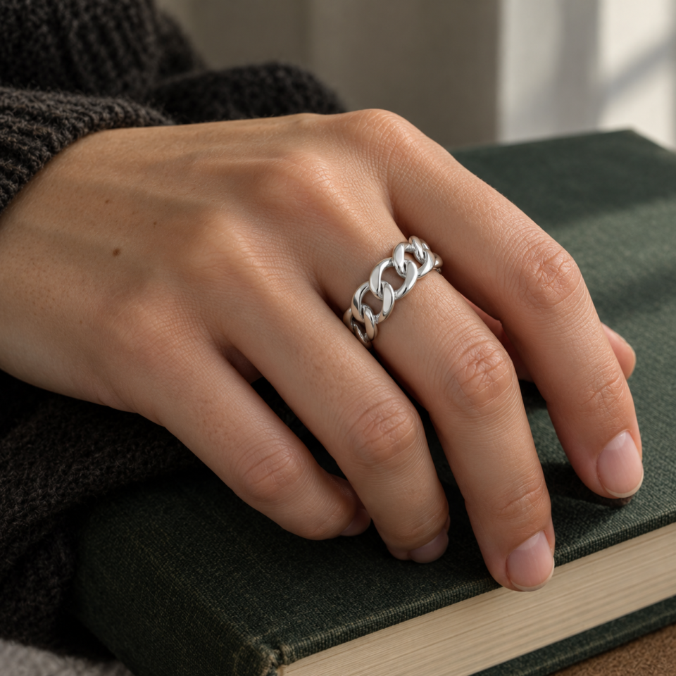 Anillo barbado de plata de ley 925 puesto en la mano sobre un libro verde