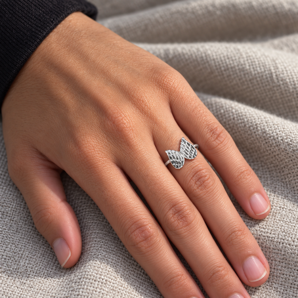 Anillo de dos alas de plata de ley 925 con relieve oxidado, puesto en una mano