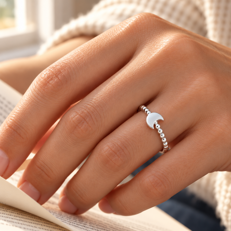 Anillo de luna con brazo de bolitas de plata de ley 925 puesto en la mano junto a un libro, referencia AN02-0041