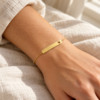 Pulsera dorada de placa con estrella calada en la muñeca de una modelo