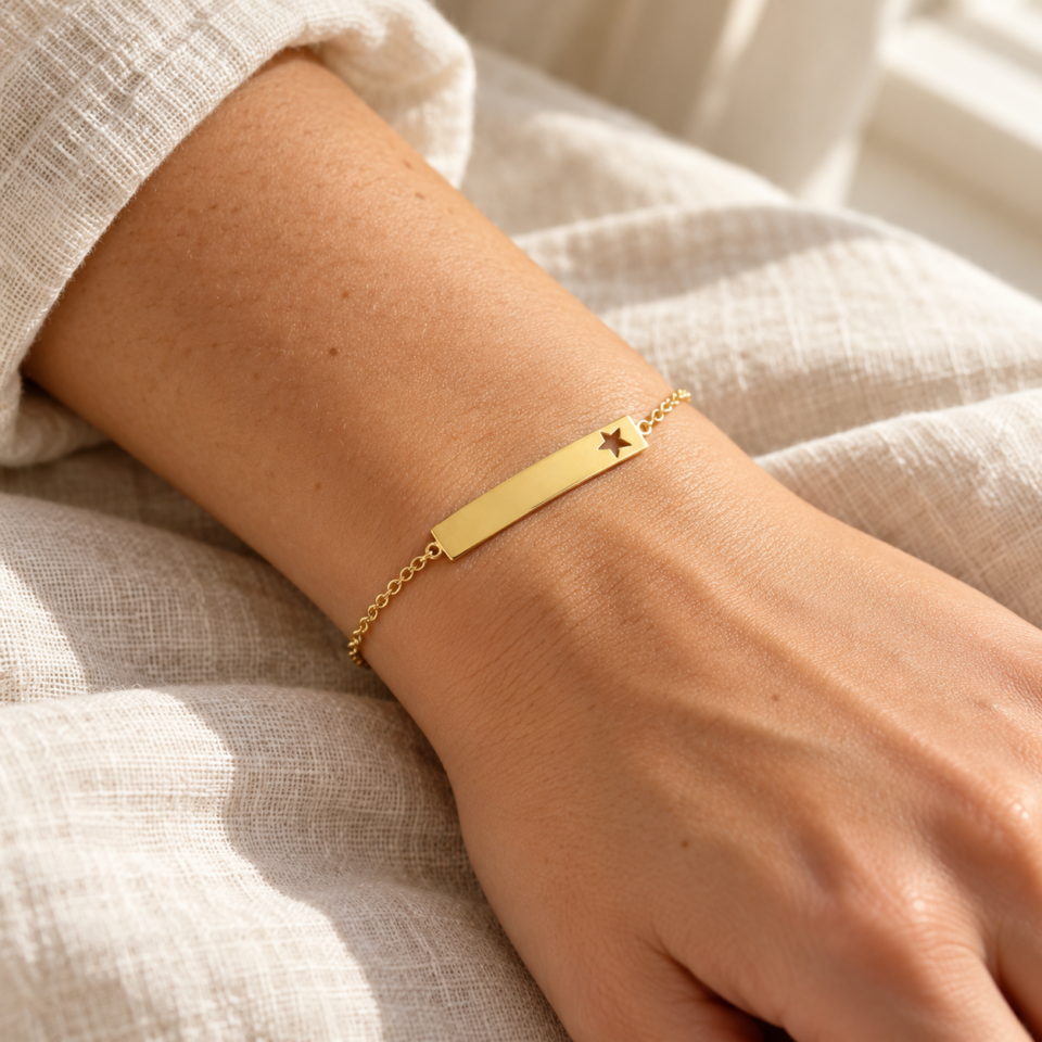 Pulsera dorada de placa con estrella calada en la muñeca de una modelo